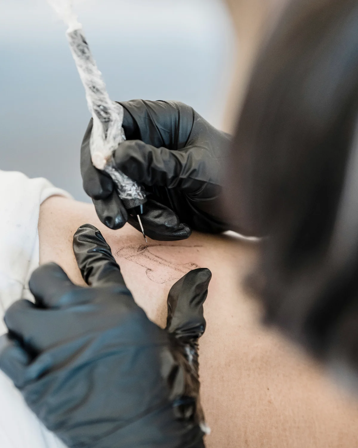 Fine-Line-Tattoo wird auf einem Unterarm gestochen